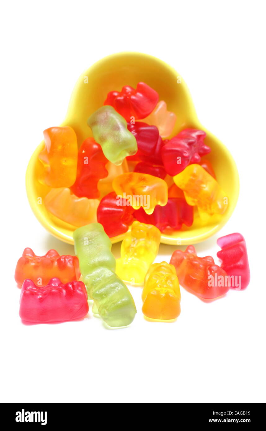 Viele bunte Haribo tragen Bonbons aus gelben Schale gießen. Isoliert auf weißem Hintergrund Stockfoto