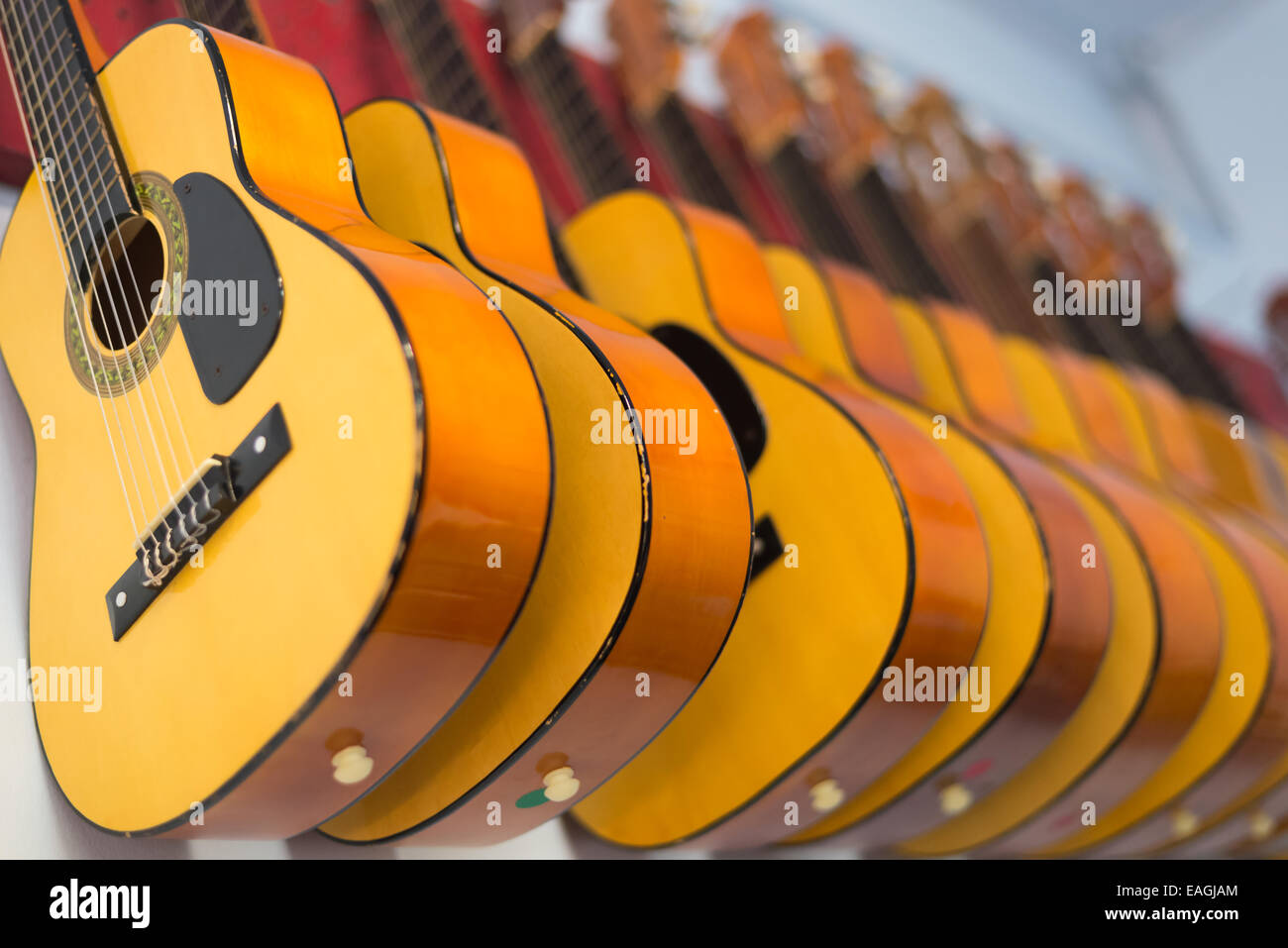 Gitarren Gitarre hängen an der Wand Musik Schule shop closeup Muster  Wiederholung gelbe Zimmer verkaufen verkaufen Stockfotografie - Alamy