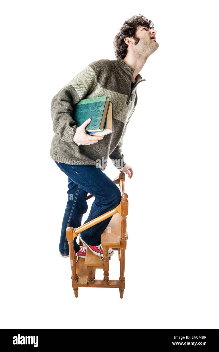 ein schöner Kerl, vielleicht ein Student in Freizeitkleidung, kletterten auf einen kleinen hölzernen Bibliotheksleiter. isoliert auf weiss Stockfoto