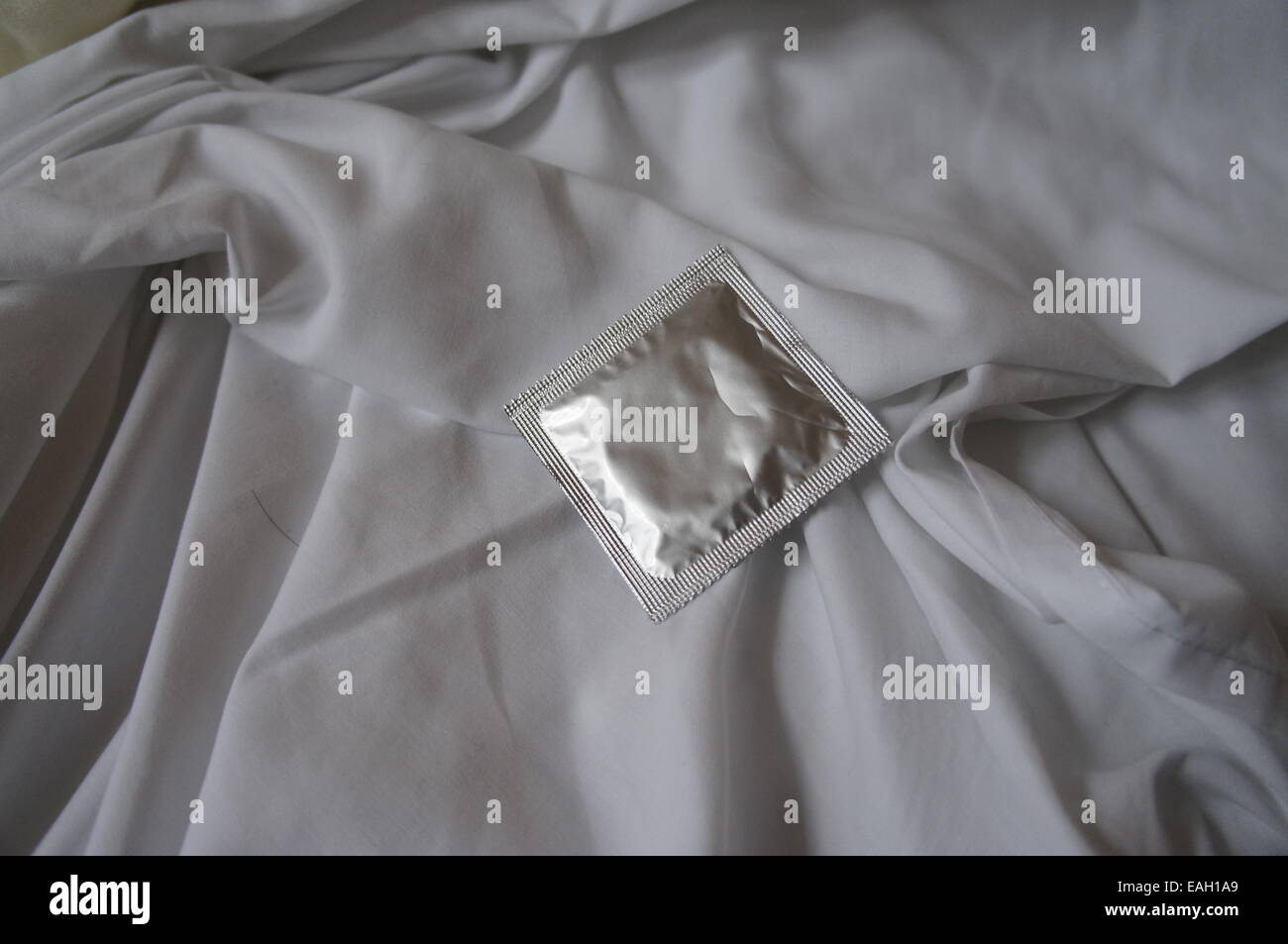 Kondom auf Bettwäsche Stockfoto