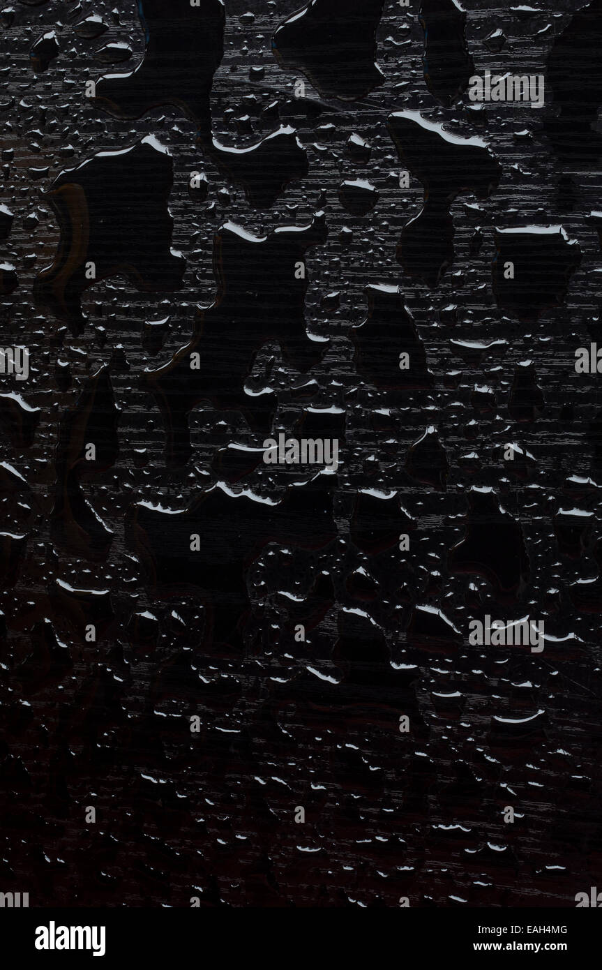 Textur der Wassertropfen auf einem schwarzen Holzsockel Stockfoto