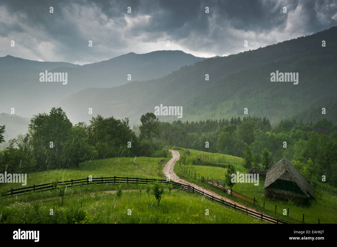 Ein Regentag in den ländlichen Bergen; eine Landstraße und ein altes Haus sind in der Nähe sichtbar. Stockfoto