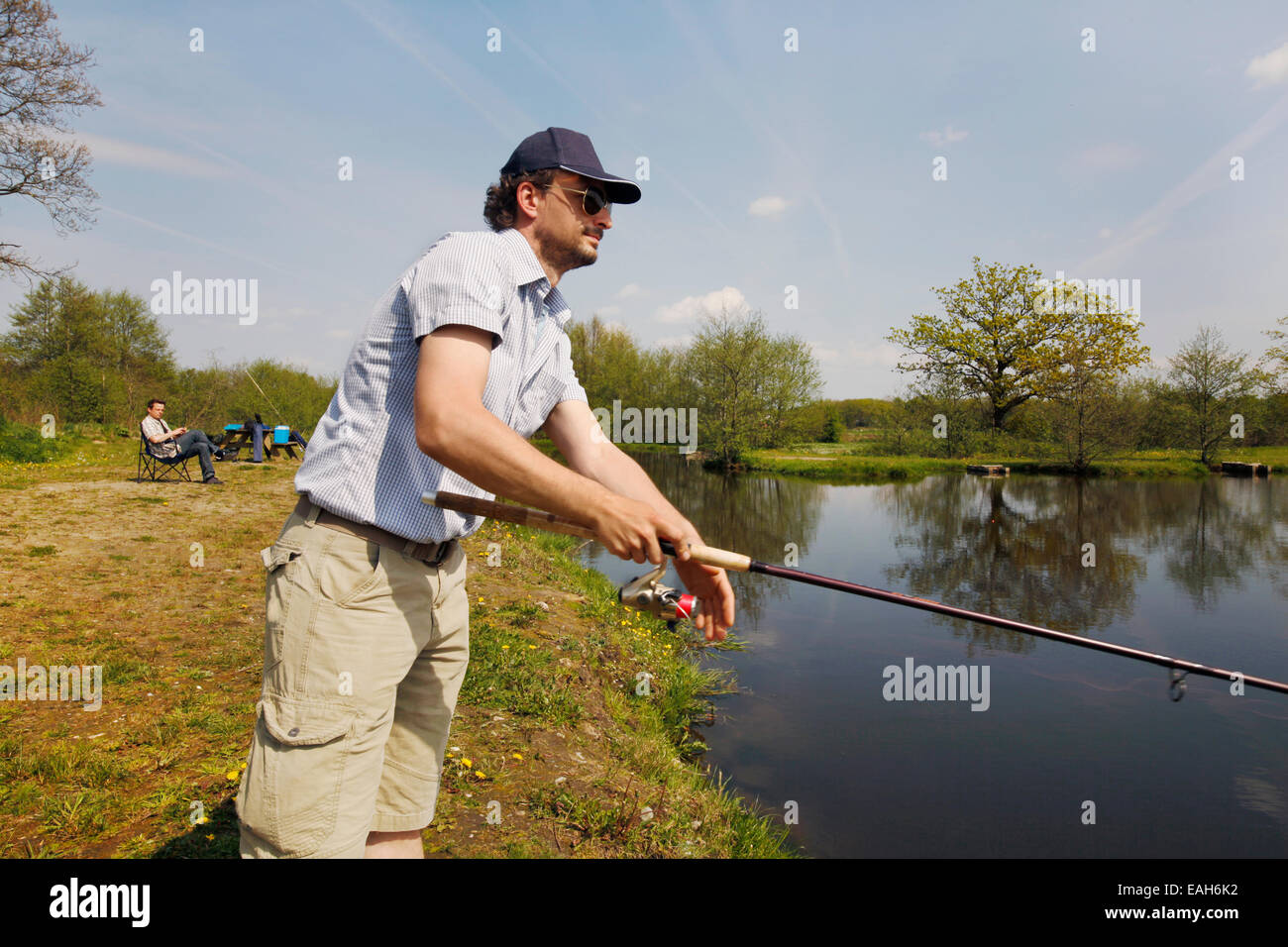 Fischer bei einem Fischteich mit Angeln Rute in der hand Stockfoto