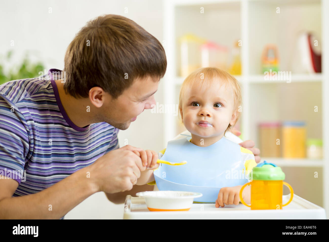 junger Vater lehrt seinen Sohn mit Löffel zu essen Stockfoto