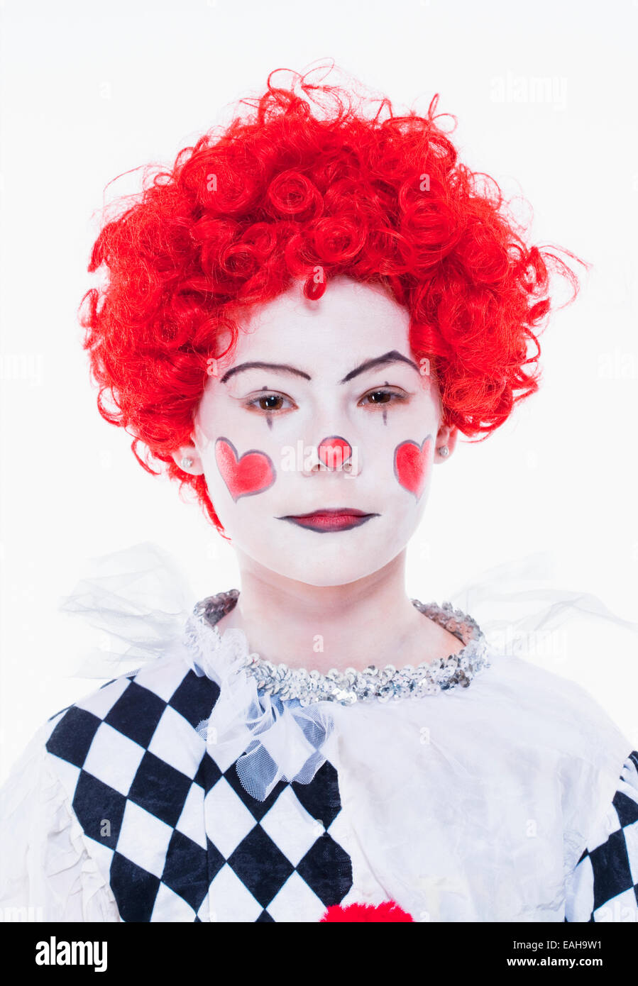 Kleines Mädchen im roten Perücke, Make-up und Outfit posiert als Clown. Stockfoto