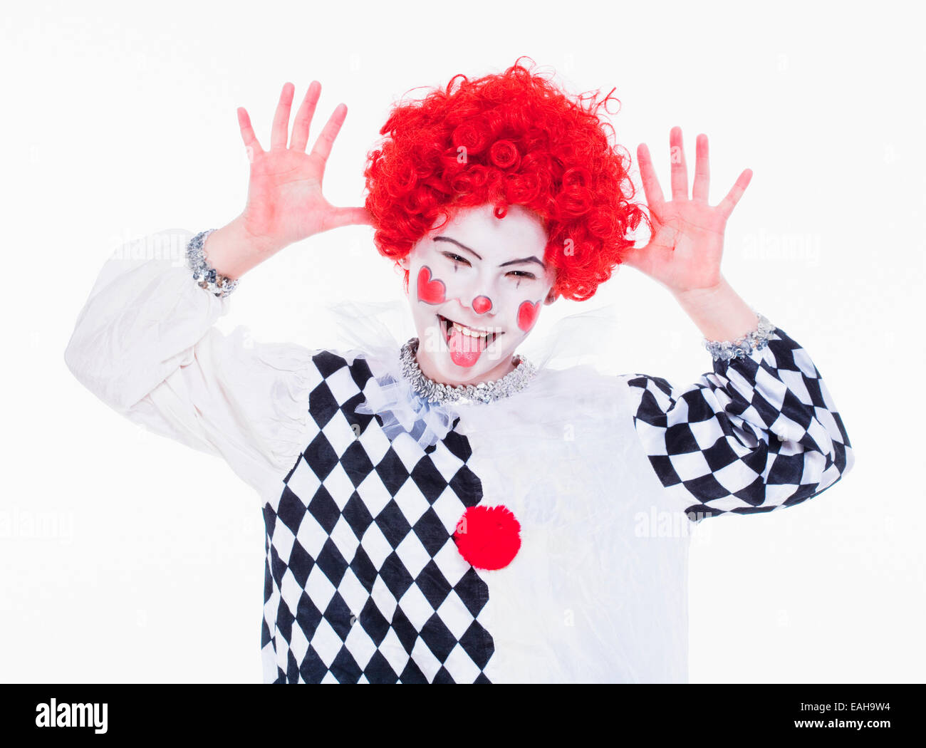 Kleines Mädchen im roten Perücke, Make-up und Outfit posiert als Clown. Stockfoto