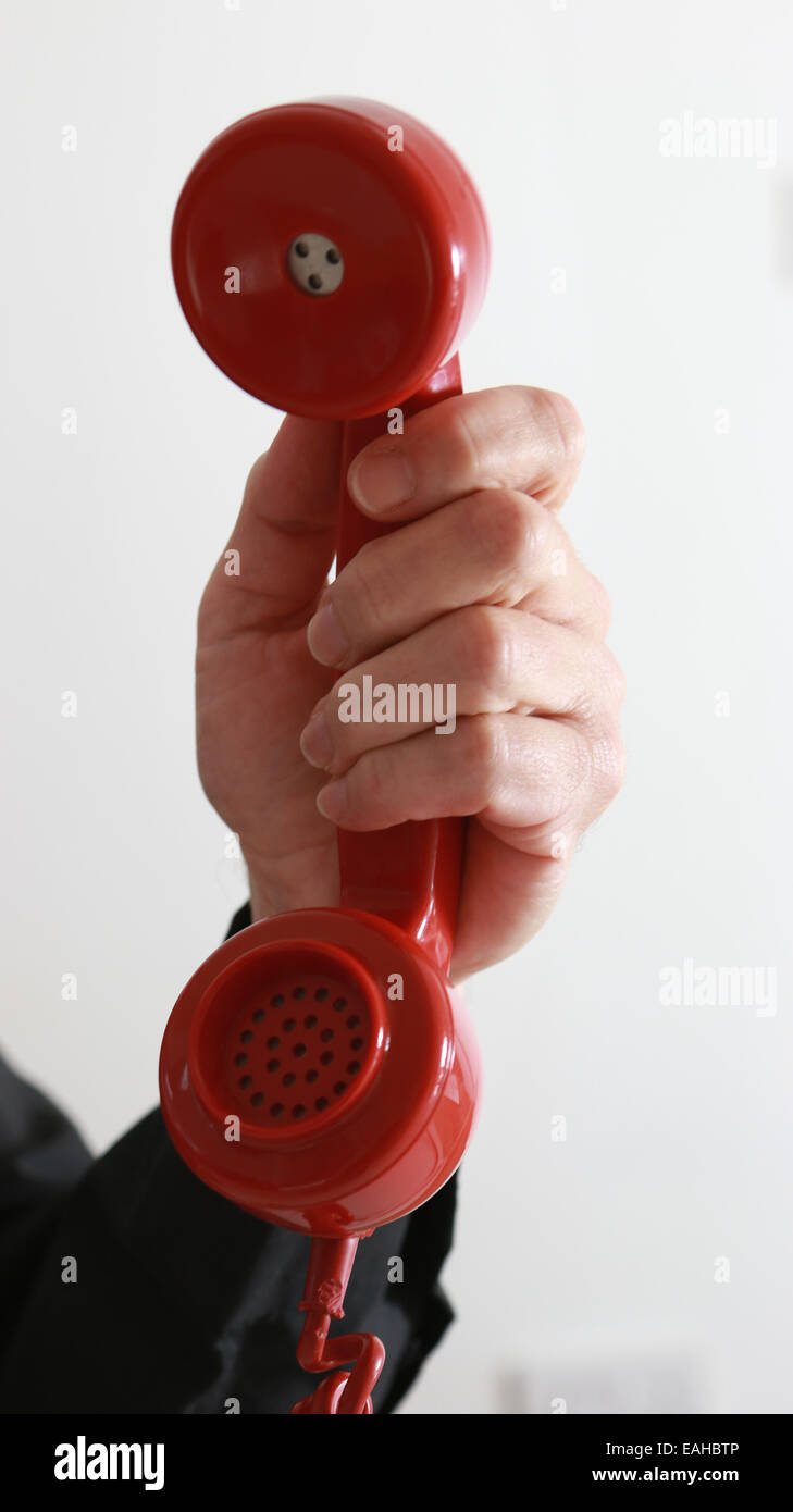 Mannes Hand hält ein alte rotes Telefon. Stockfoto