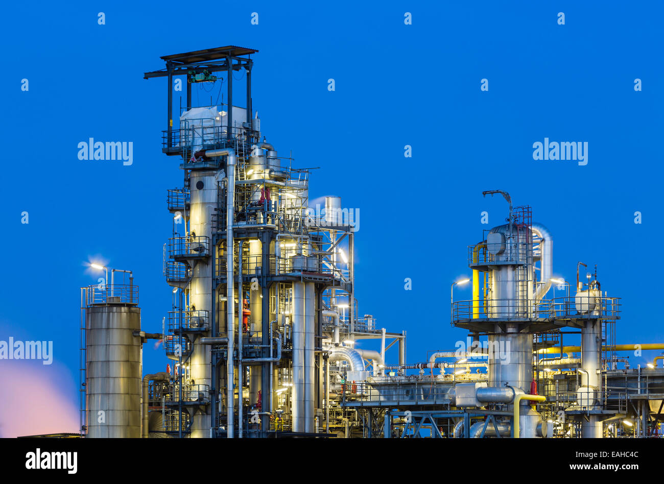 Blick auf die Türme der Destillation einer Chemiefabrik und Raffinerie mit blauen Nachthimmel und Beleuchtung. Stockfoto