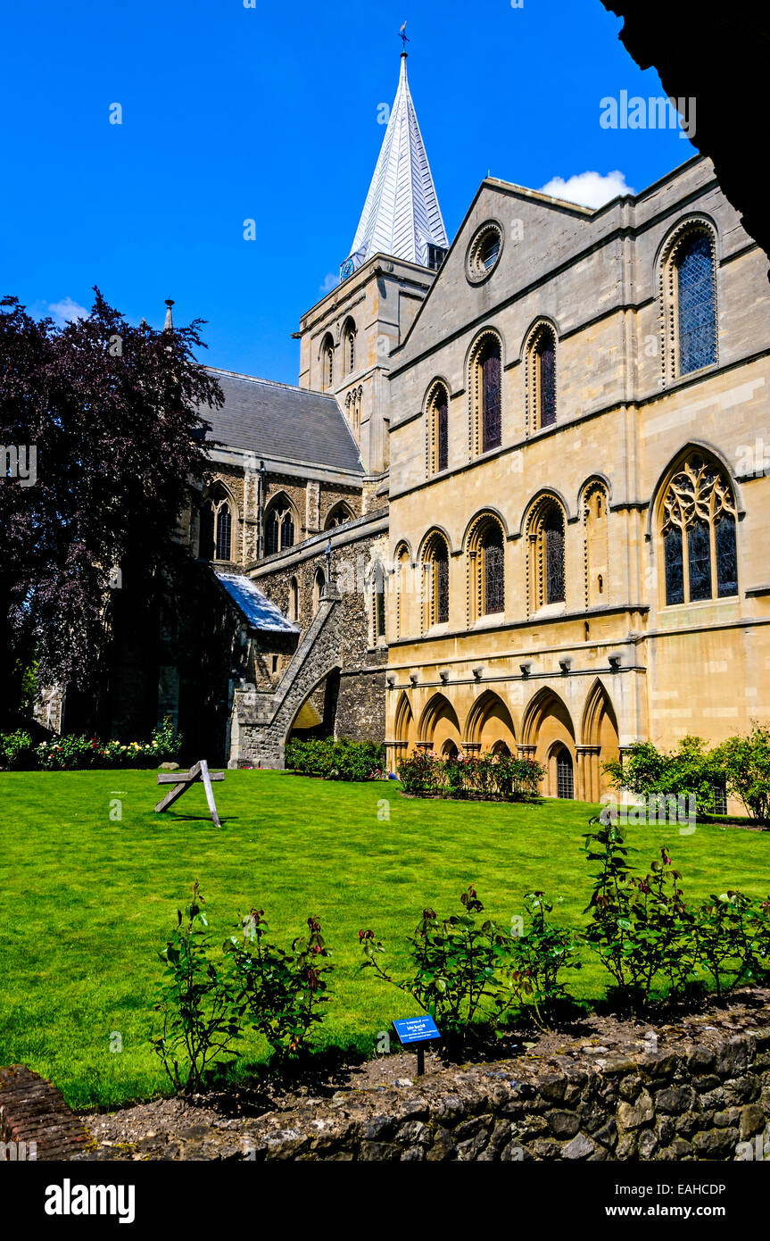 Das imposante Äußere des Rochester Kathedrale zeigt Kapitel Haus und Garten mit einer gebrochenen hölzernen Kreuz auf einer gemähten Wiese Stockfoto