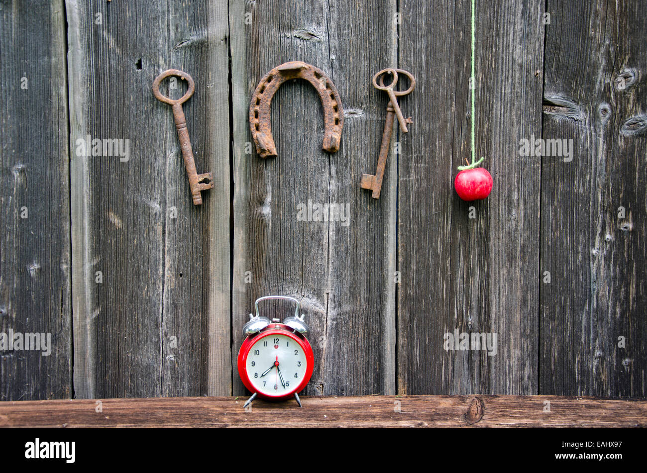 Vintage rostigen Hufeisen, Apple, Schlüssel und Uhr auf Holzwand Stockfoto