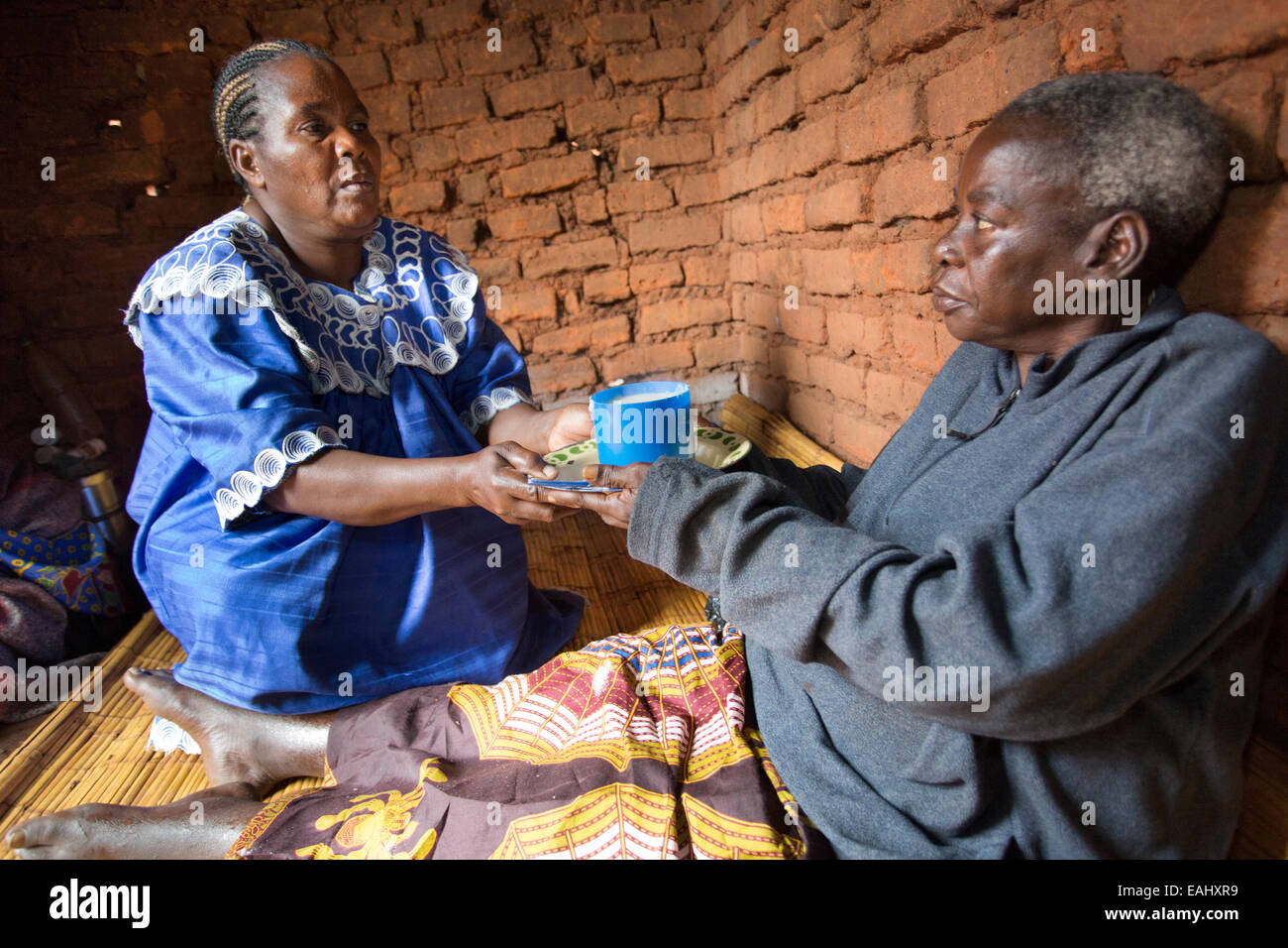 Eine Frau sorgt für einen älteren kranken Patienten zu Hause in Mulanje Bezirk, Malawi. Stockfoto