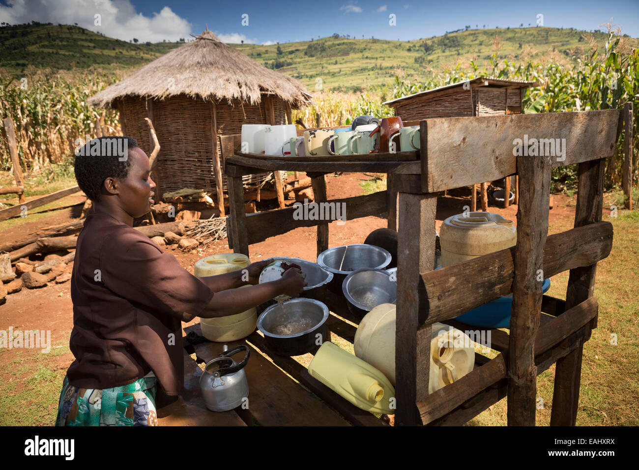 Eine Frau trocknet Gerichte auf einem Teller Wäscheständer vor ihrem Haus in Ndishania Dorf, Bukwo District, Uganda. Stockfoto