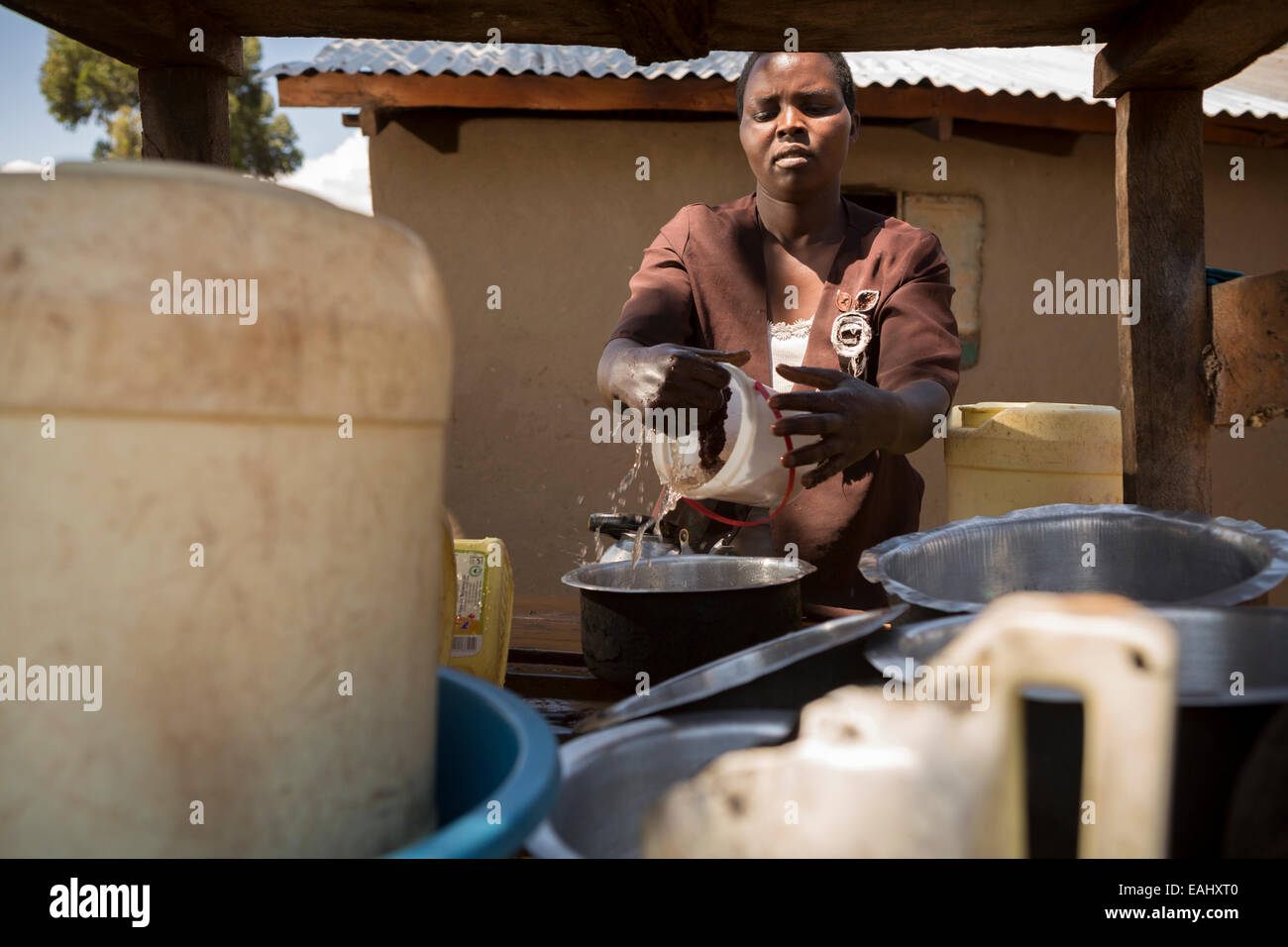 Eine Frau trocknet Gerichte auf einem Teller Wäscheständer vor ihrem Haus in Ndishania Dorf, Bukwo District, Uganda. Stockfoto