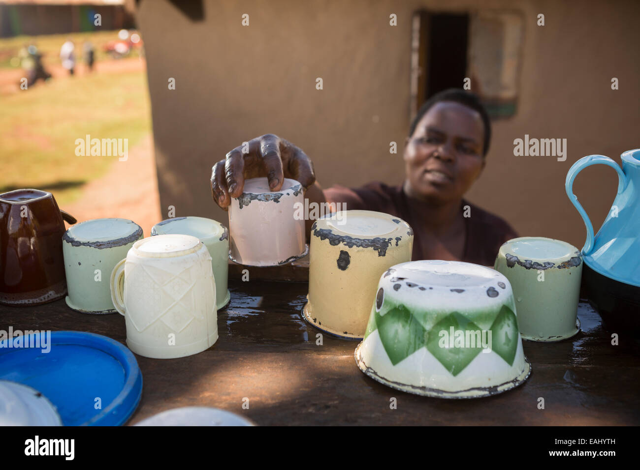 Eine Frau trocknet Gerichte auf einem Teller Wäscheständer vor ihrem Haus in Ndishania Dorf, Bukwo District, Uganda. Stockfoto