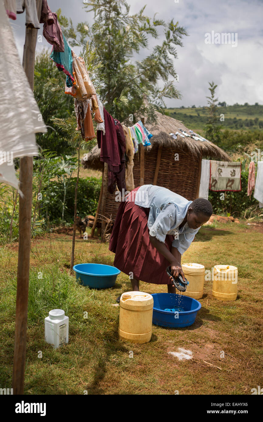 Eine Frau wäscht und trocknet Kleidung auf ihrem Hof im Bukwo District, Uganda. Stockfoto