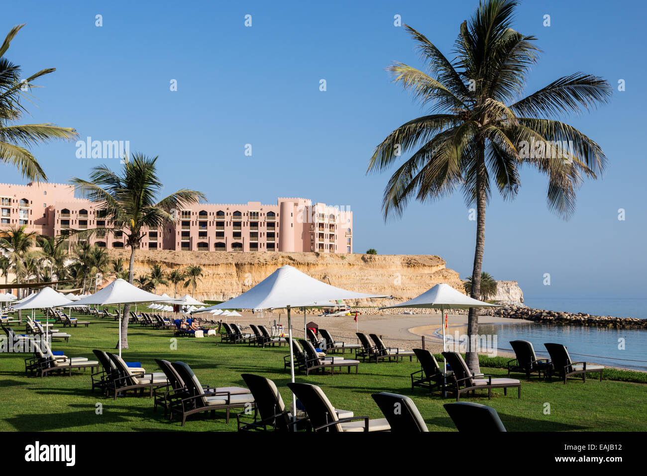 Strandkörbe und Grünflächen entlang des Sandstrandes in einem Luxus-Resort. Muscat, Oman. Stockfoto