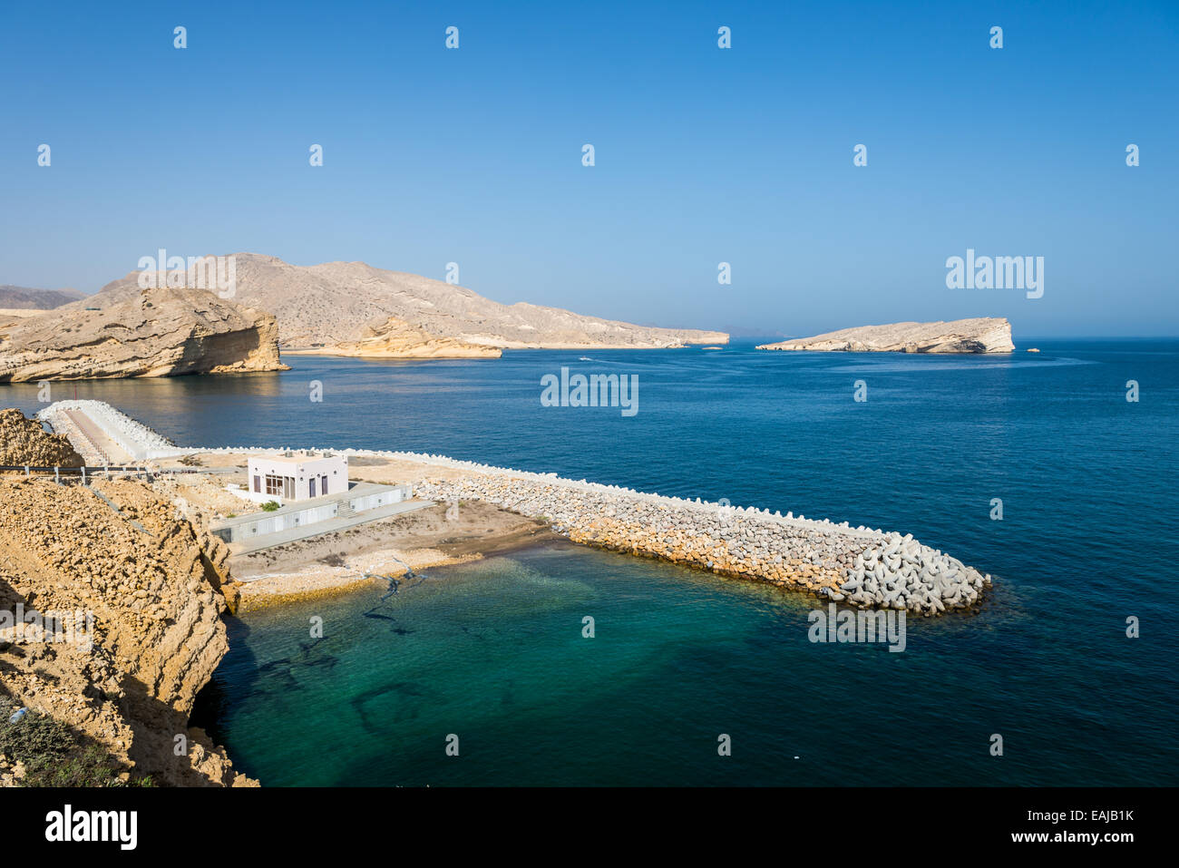 Kalksteinfelsen steht über dem blauen Wasser des Arabischen Meeres. Oman. Stockfoto