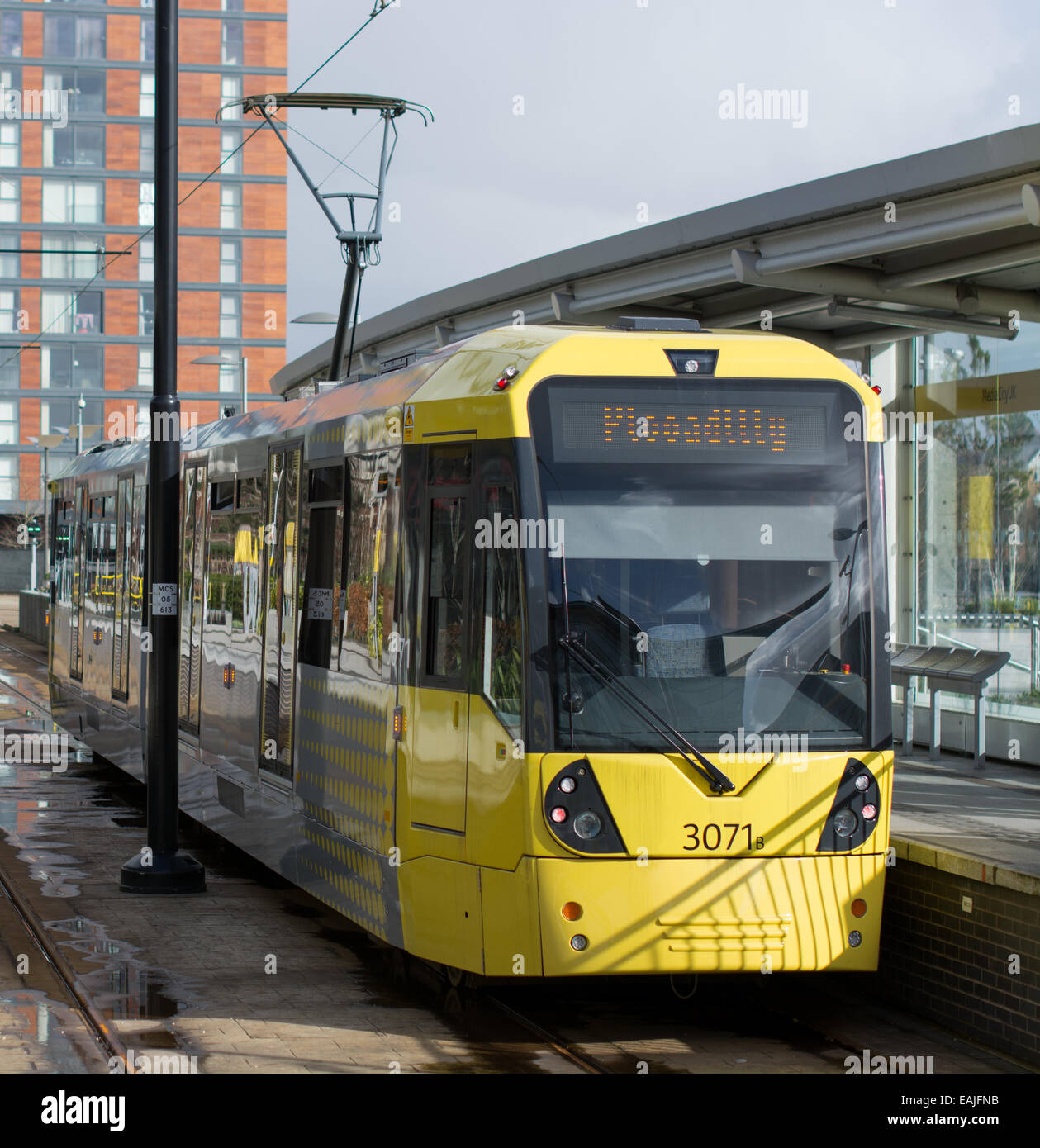 Eine gelbe Metrolink-Straßenbahn hochgezogen auf einer Plattform vor der Abreise zu Manchester Piccadilly. Stockfoto