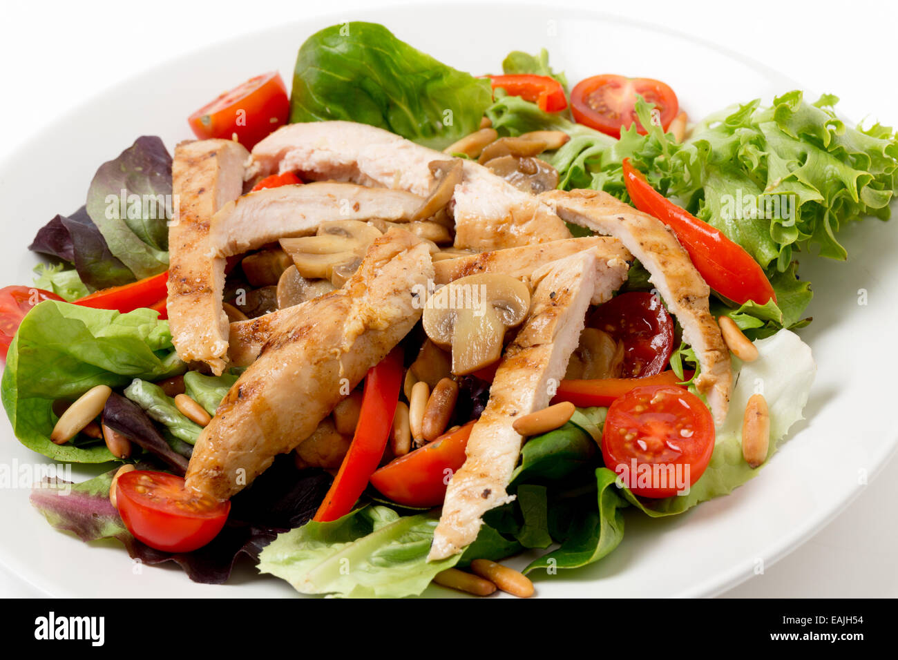 Warm Chicken und Pilzsalat mit Salat, Kirschtomaten, Pinienkernen und Streifen von Paprika Stockfoto