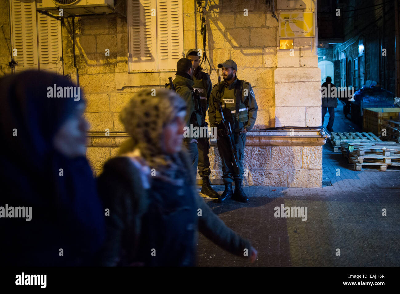 (141116)--JERUSALEM, 16. November 2014 (Xinhua)--israelische Polizisten Wache stehen als arabische Frauen Spaziergang vorbei an der Szene, wo ein jüdischer Mann im Zentrum von Jerusalem, am 16. November 2014 erstochen wurde. Ein jüdischer Mann im Zentrum von Jerusalem Sonntagabend in einem scheinbaren militante Angriff erstochen wurde, sagte Polizei-Sprecher Mickey Rosenfeld Xinhua. Das Opfer in seinen frühen dreißiger Jahren, wurde auf der Rückseite mit einem Schraubenzieher erstochen und gelitten moderate Wunden in Hanevi'im Straße im Zentrum von Jerusalem. Er wurde in der Sha'are Tzedek Medical Center in die Stadt gebracht. Der Verdächtige ist zu groß und die Polizei haben Straßensperren errichtet Stockfoto