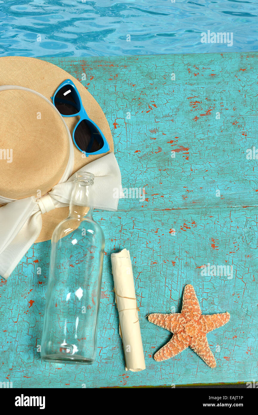 Hut; Sonnenbrille, Flasche mit Meldung und Seestern auf lackierten Holzplatten Stockfoto