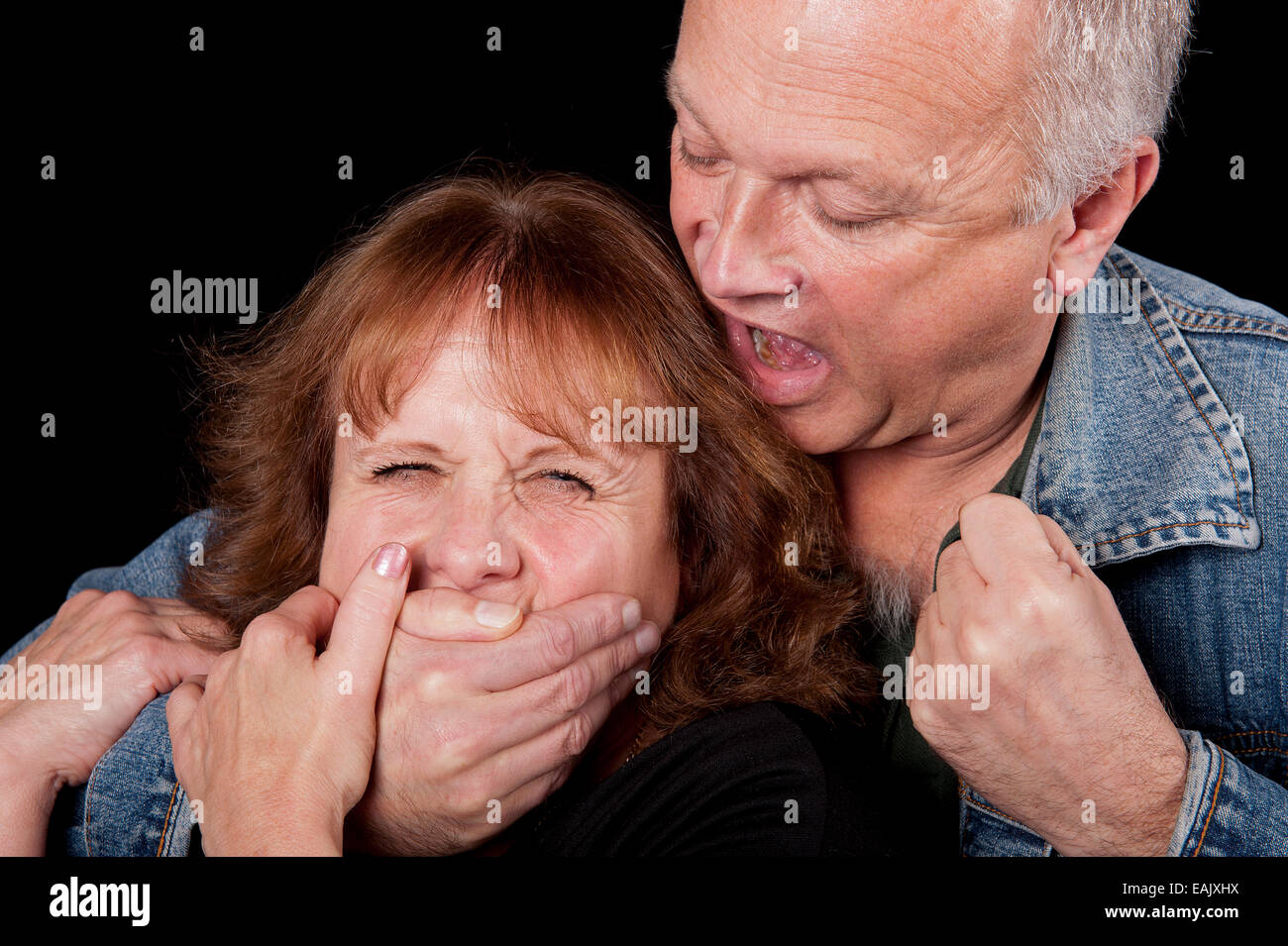 Mann, eine Frau von hinten packte und droht ihr mit der Faust. Stockfoto