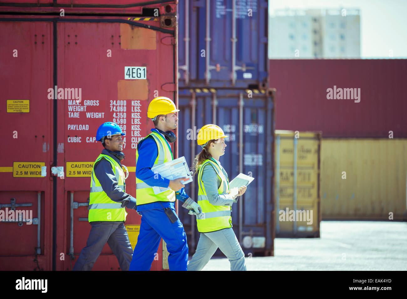 Geschäftsleute und Arbeiter zu Fuß in der Nähe von Containern Stockfoto