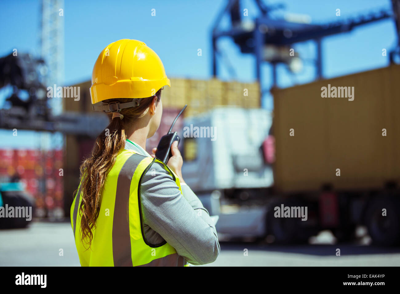 Geschäftsfrau mit Walkie-talkie in der Nähe von Containern Stockfoto