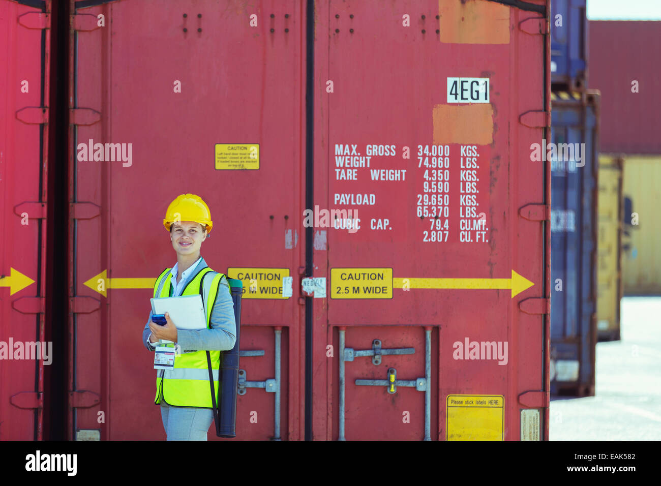 Geschäftsfrau, die lächelnd in der Nähe von Containern Stockfoto