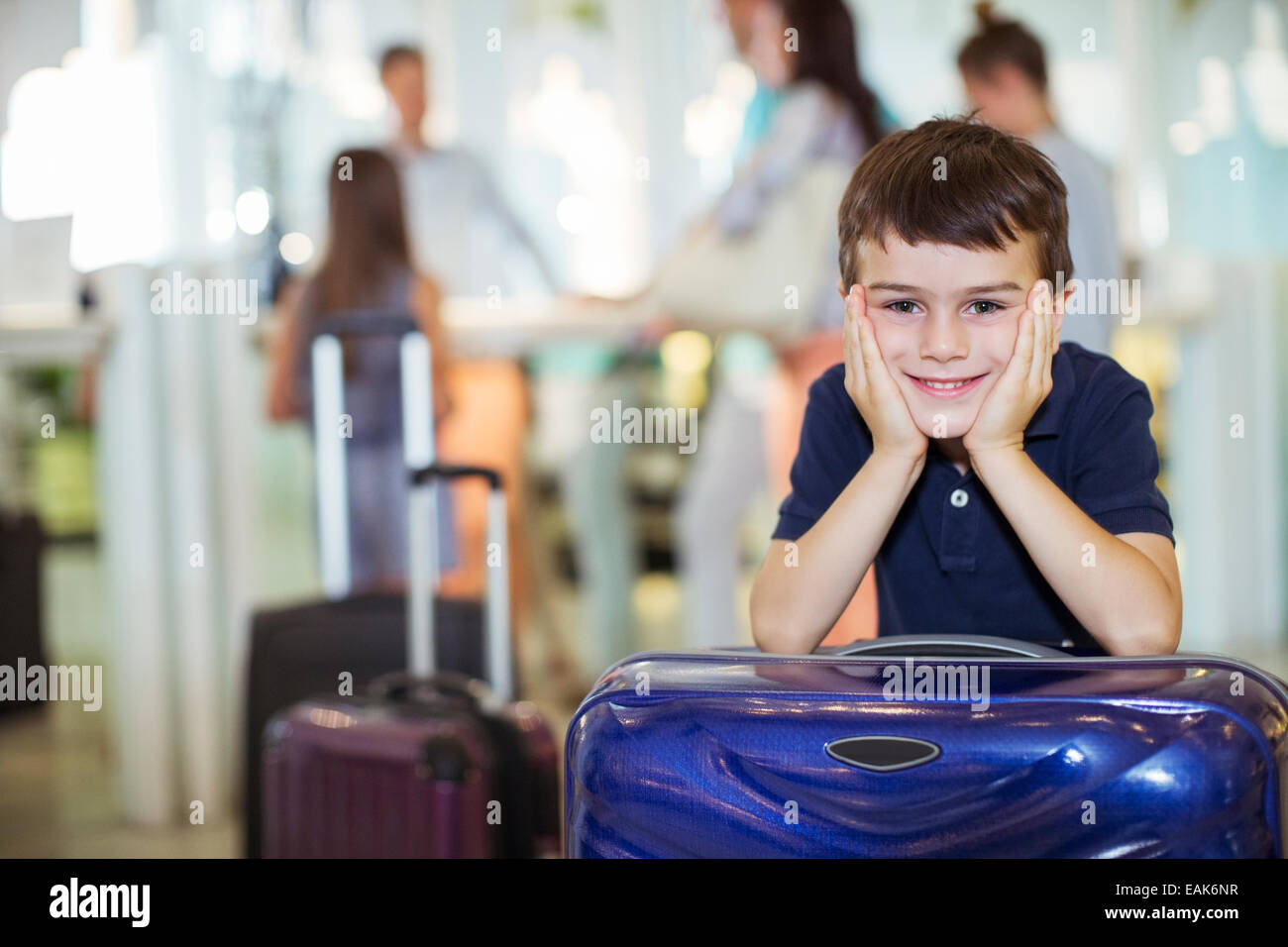 Porträt eines lächelnden jungen stützte sich auf Koffer in der Lobby des Hotels Stockfoto