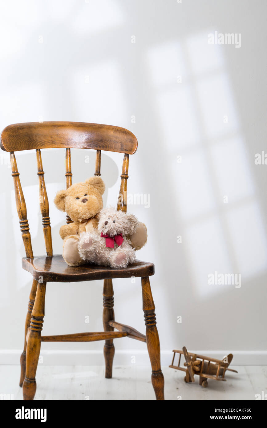 Zwei Teddybären sitzend auf einem Stuhl mit Sonnenlicht durchströmen Stockfoto