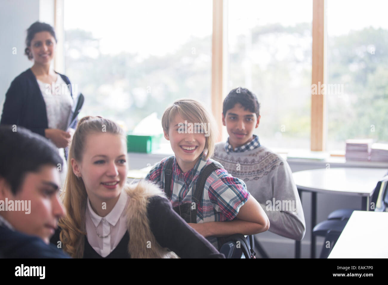Fröhliche Schülerinnen und Schüler mit ihrem Lehrer im Klassenzimmer Stockfoto