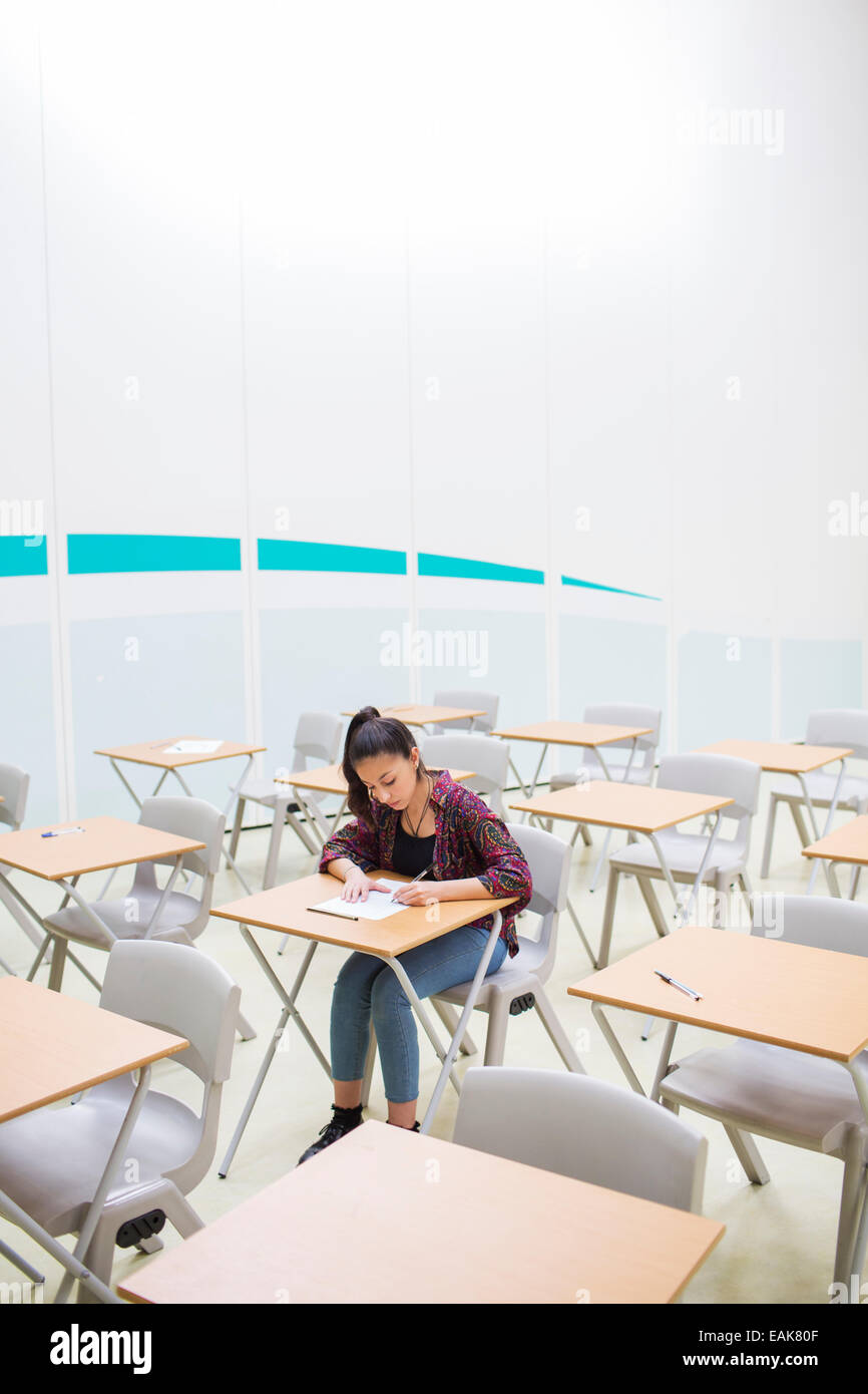 Studentin während GCSE Prüfung allein im Klassenzimmer sitzen Stockfoto