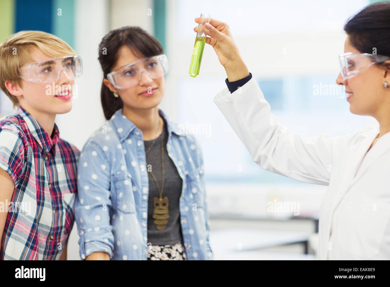 Schüler mit ihrem Lehrer arbeiten im Chemielabor, Lehrer hält Reagenzglas mit grüner Flüssigkeit Stockfoto