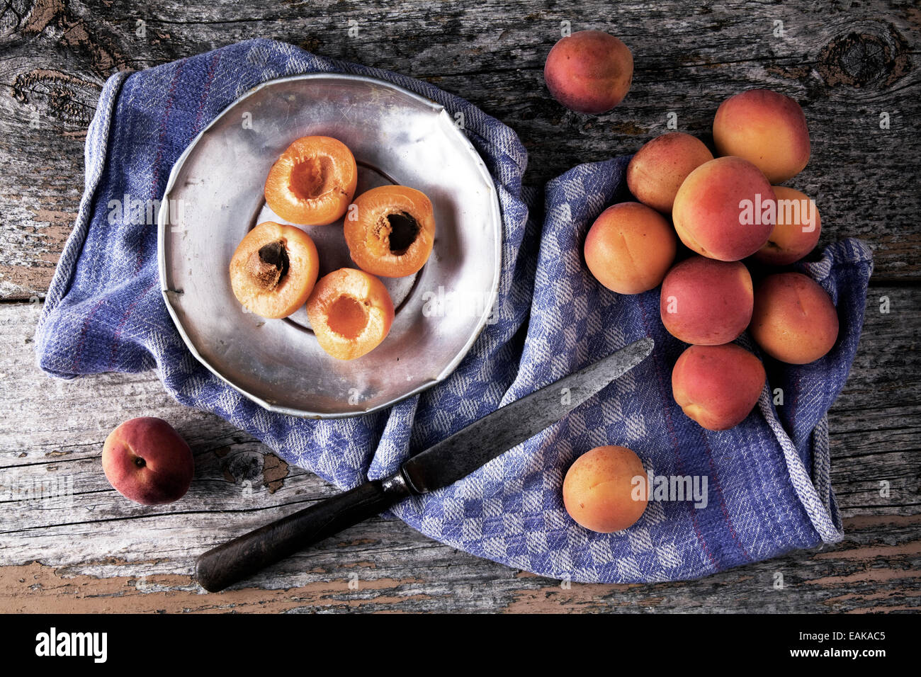 Frische Aprikosen auf einem Zinn Teller, mit einem Messer und Küche Handtuch auf einem hölzernen Hintergrund Stockfoto