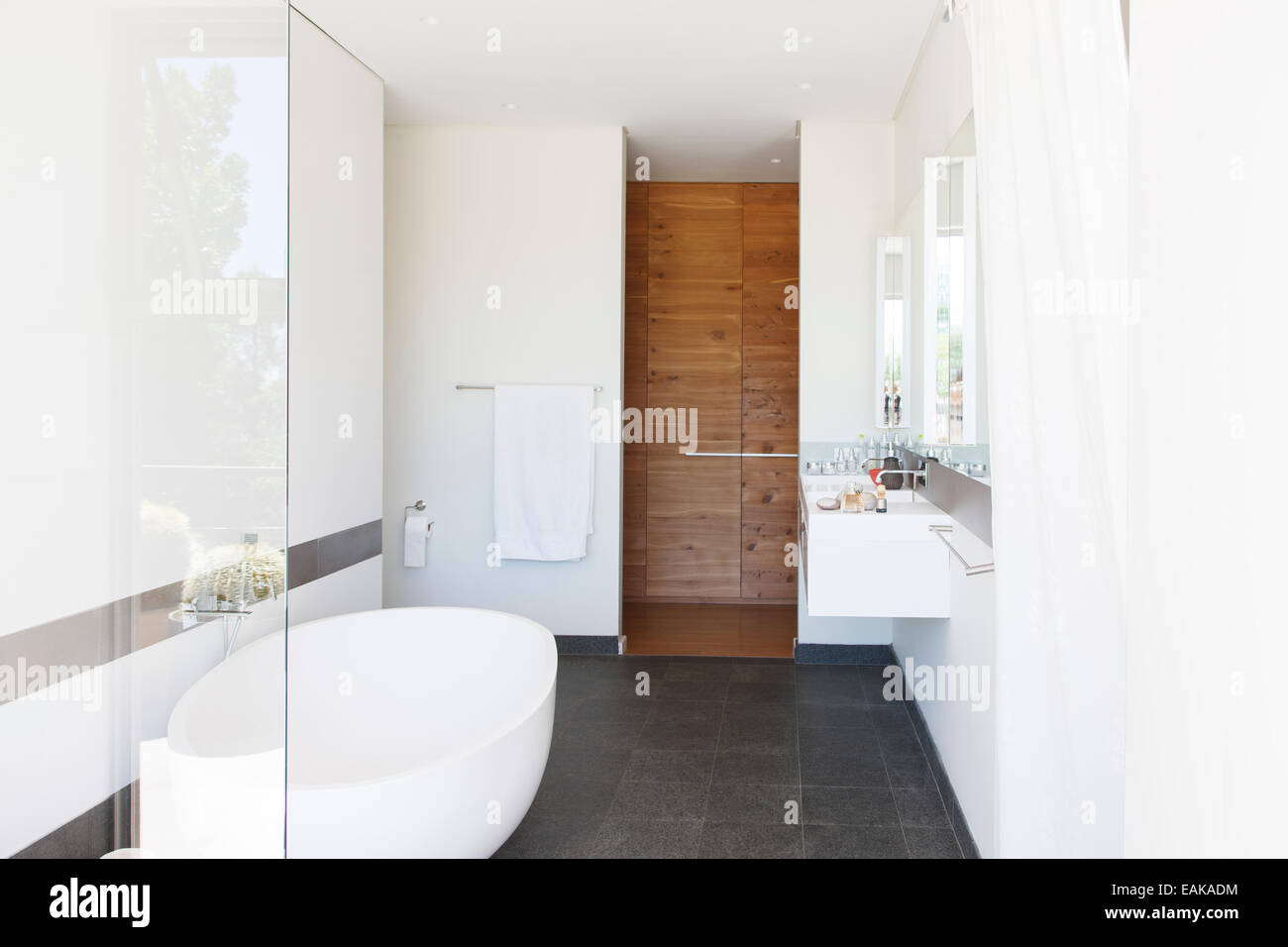 Modernes Badezimmer Interieur mit großer Badewanne und Holztür Stockfoto