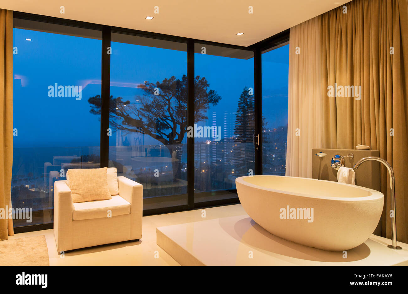 Blick auf luxuriöses Badezimmer mit Badewanne und Sessel in der Nacht Stockfoto