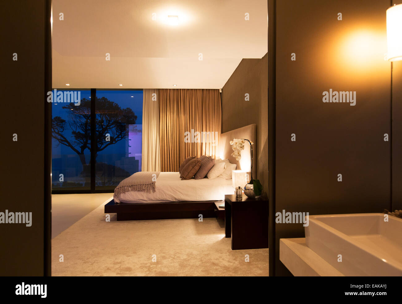 Beige und weiß Schlafzimmer mit Doppelbett, gesehen vom Bad in der Nacht Stockfoto