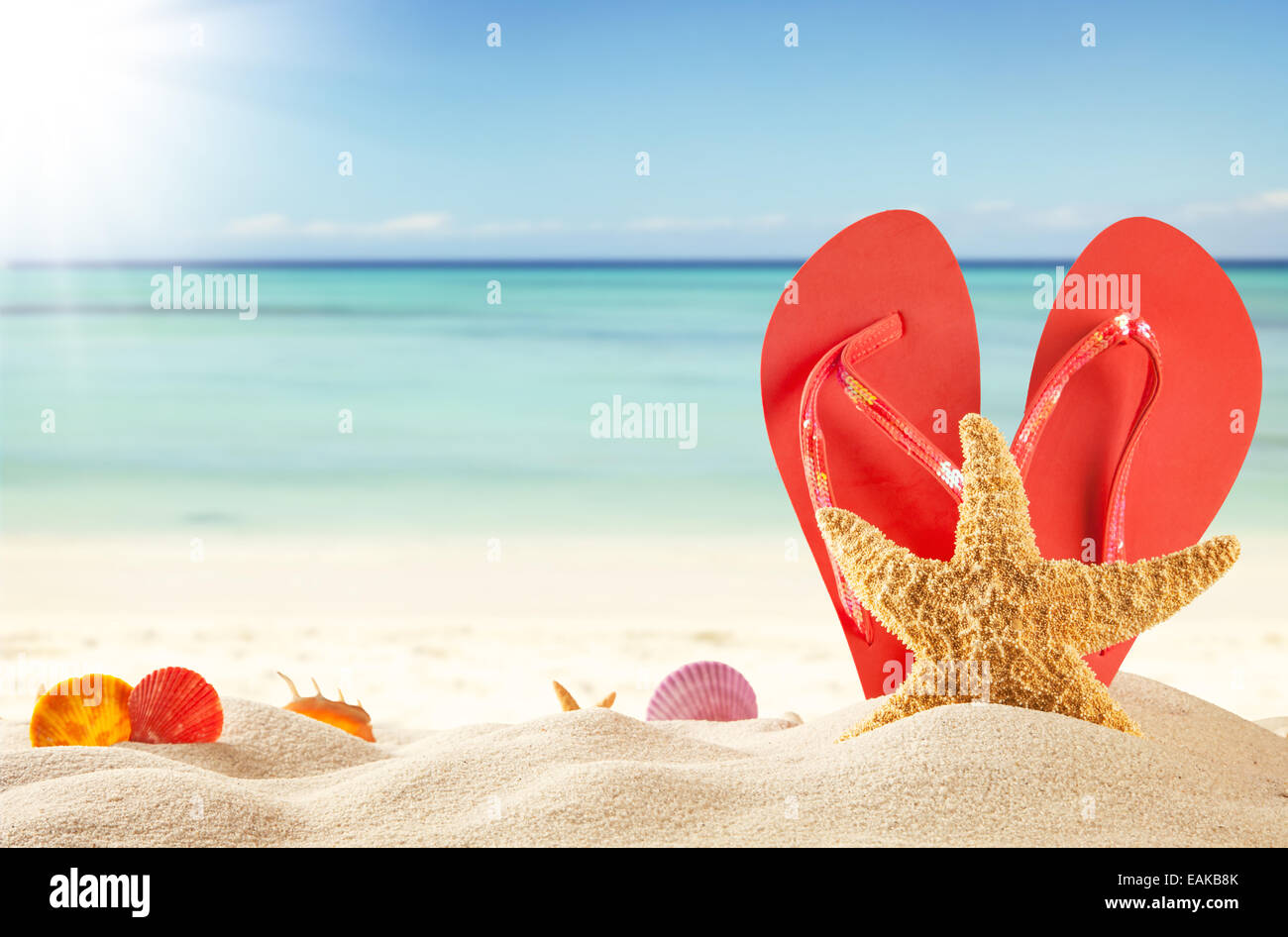 Sommer-Konzept mit Sandstrand, Muscheln und rote Sandalen Stockfoto