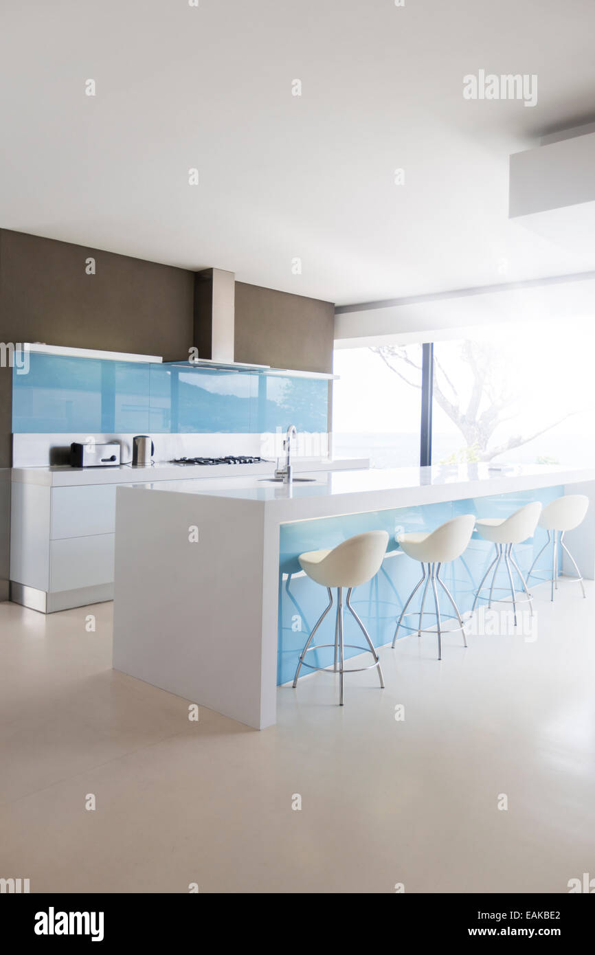 Weiße und saubere moderne Küche mit Hockern bei Kücheninsel Stockfoto