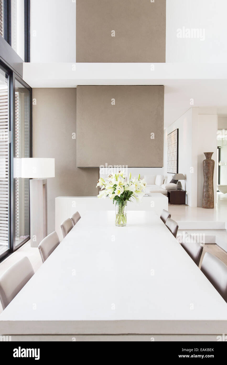 Moderne weiße und Beige Esszimmer mit großem Tisch und Lilien in vase Stockfoto