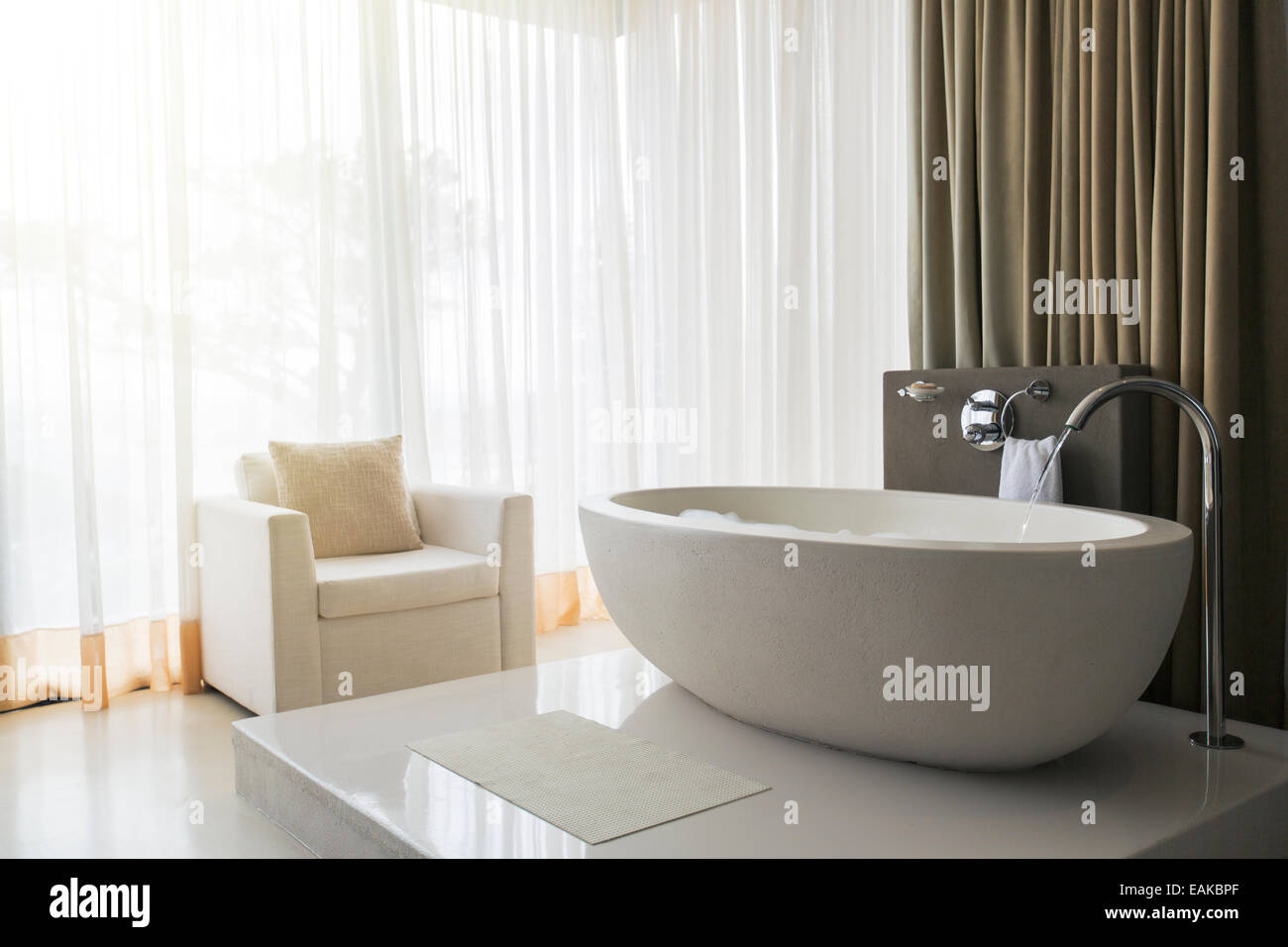 Blick auf moderne und luxuriöse Badezimmer mit Badewanne und Sessel Stockfoto