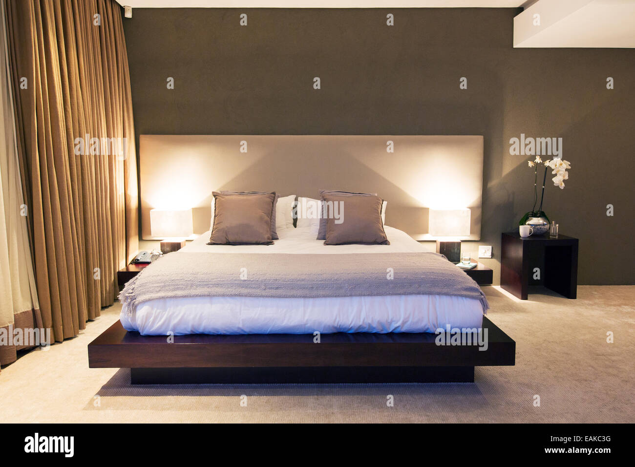 Moderne Schlafzimmer mit Doppelbett, die nachts beleuchtet Stockfoto