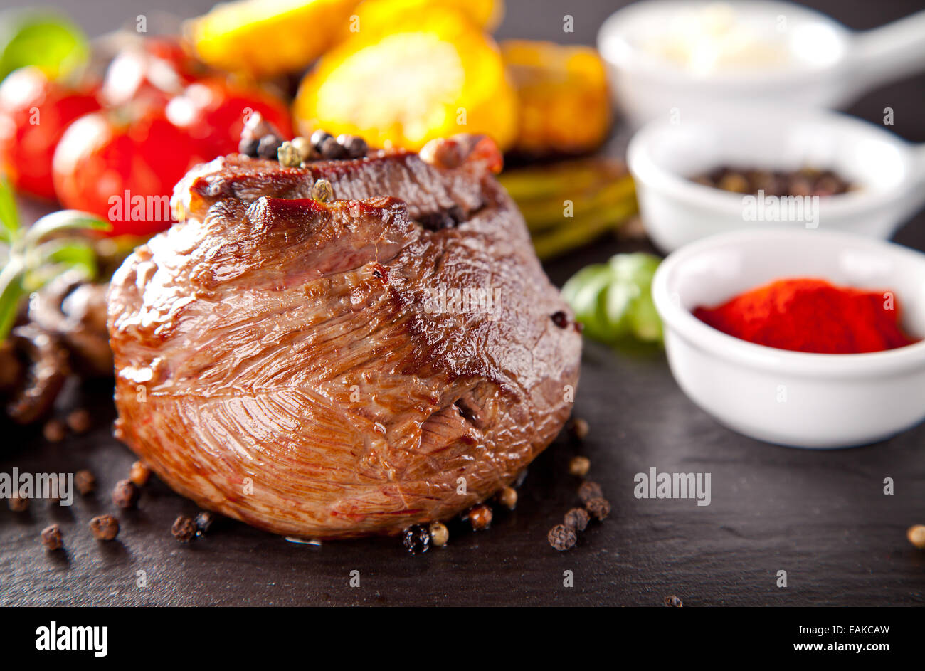 Rindersteak, serviert mit gegrilltem Gemüse und Kräuter auf schwarzen Steintisch Stockfoto