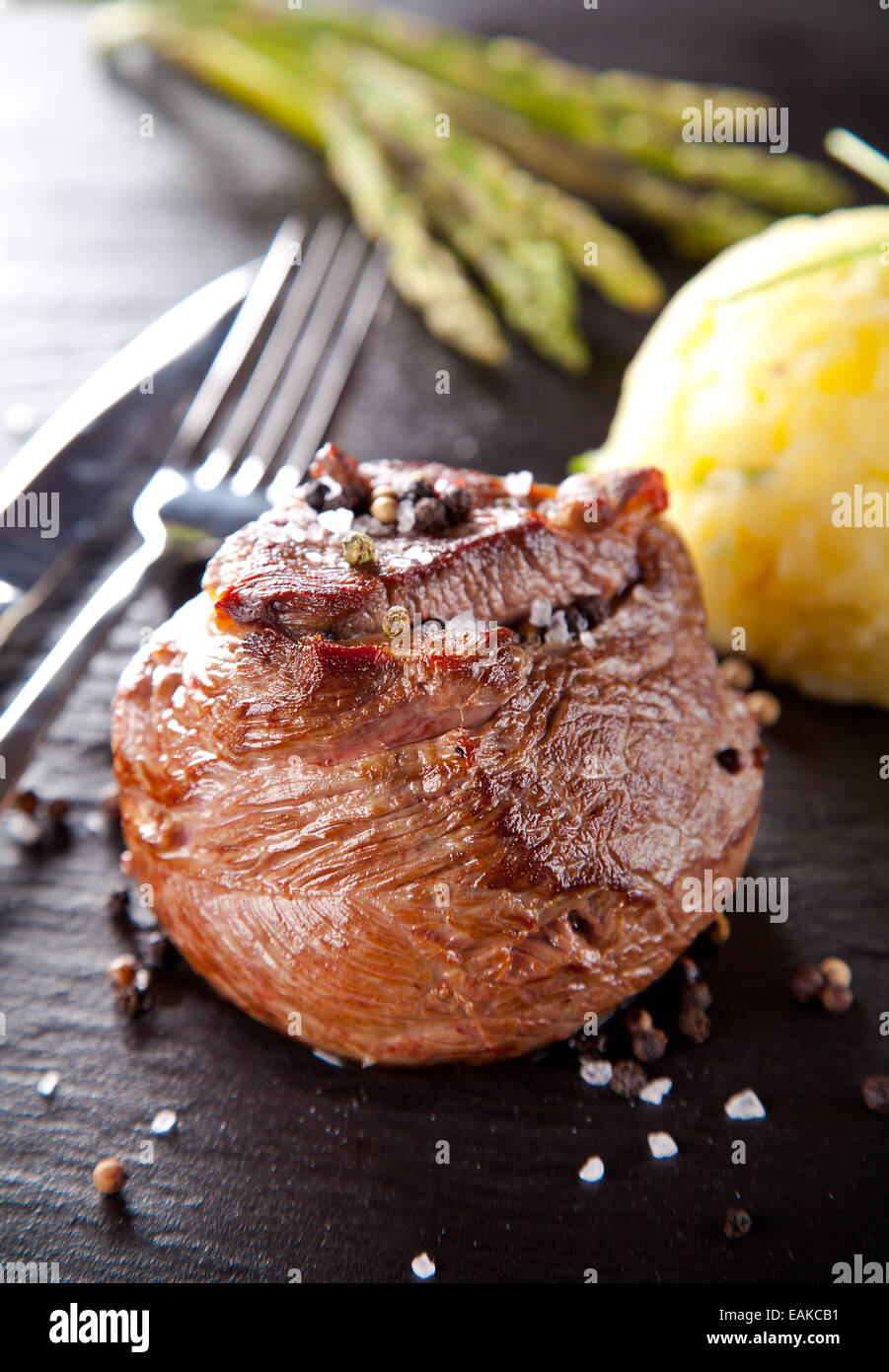 Rindersteak, serviert mit gegrilltem Gemüse und Kräuter auf schwarzen Steintisch Stockfoto