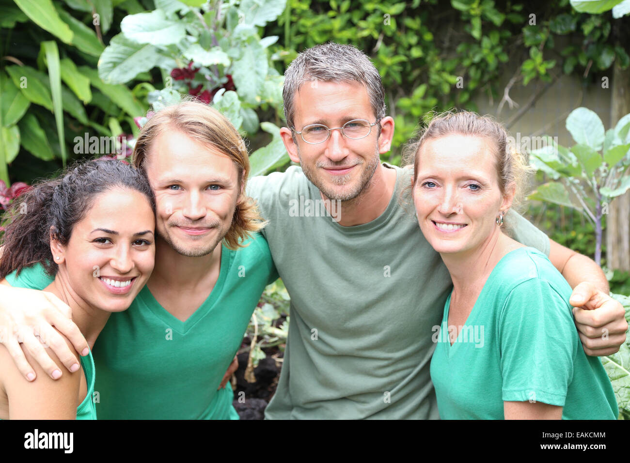 Porträt von vier Männern und Frauen tragen grüne T-shirts im Garten Stockfoto