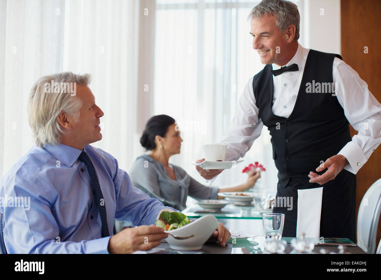 Kellner servieren Tasse Kaffee, reifer Mann sitzt am Tisch im