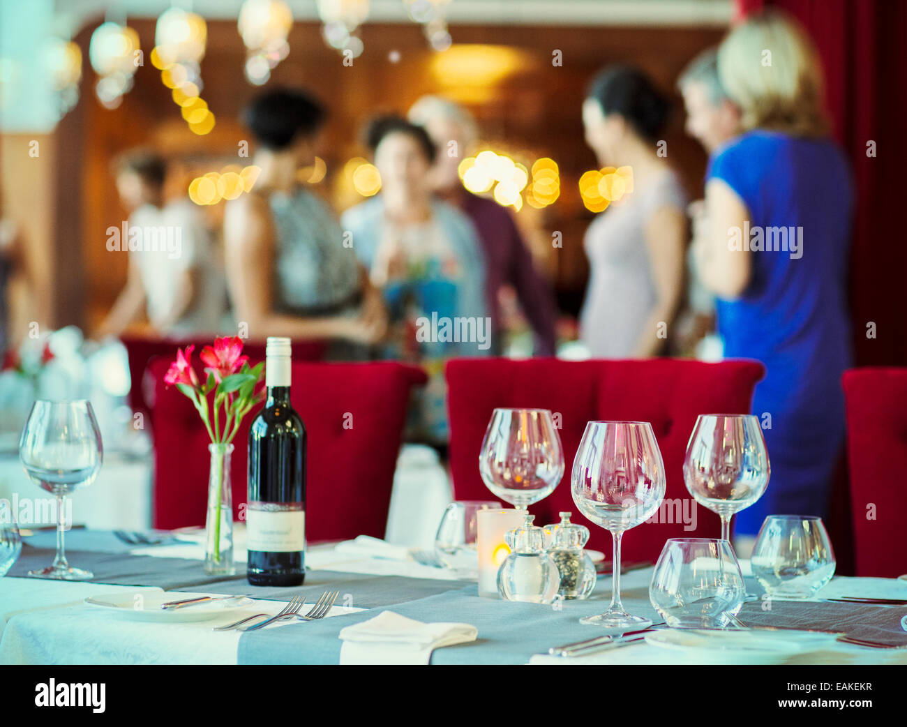Weingläser und Flasche Rotwein am Tisch im Restaurant, Menschen im Hintergrund Stockfoto