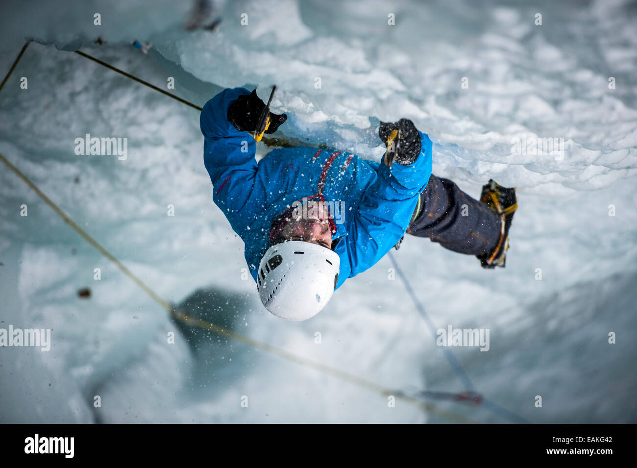 Mann im Schwierigkeitsklettern einen Eisfall mitten in einem Schneesturm in Simplon-Pass, Wallis, Schweiz. Stockfoto