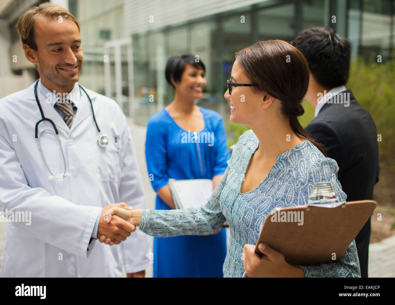 Lächelnd schüttelte die Hand mit Frau vor Krankenhaus Arzt Stockfoto